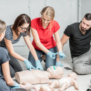 a group of people around adult and infant cpr training aids