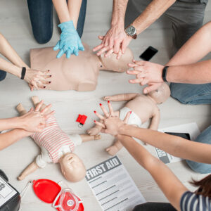 a group of people holding out their hands to practice cpr on first aid training aids